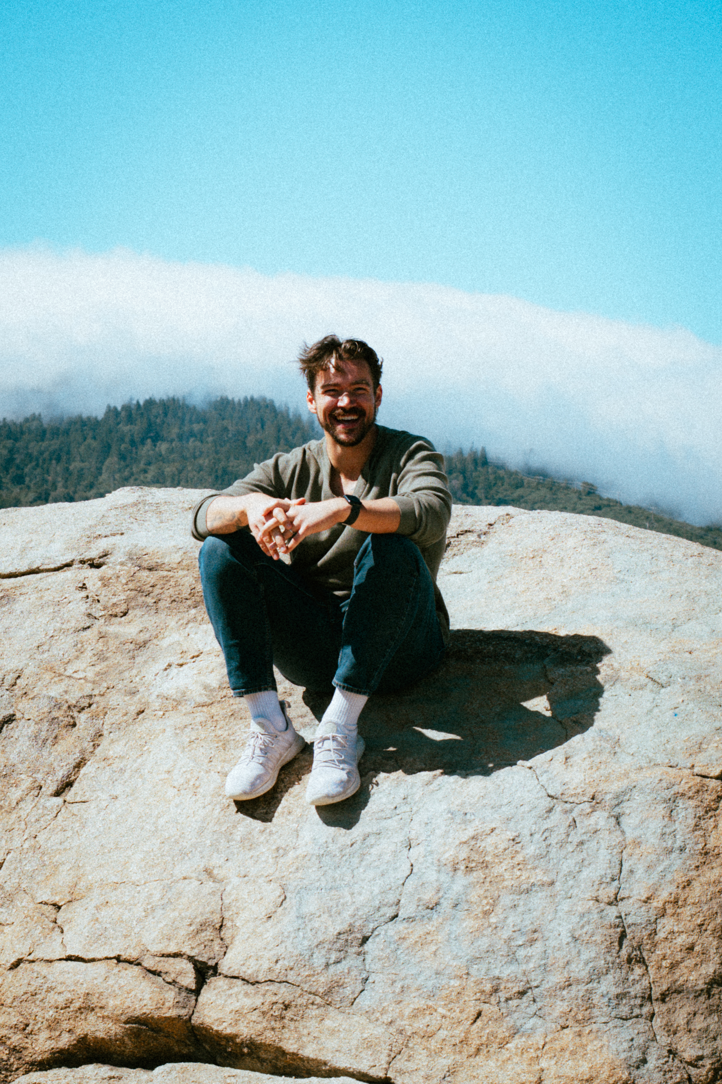 Jack Bontatibus sitting on a sunlit rock in the mountains